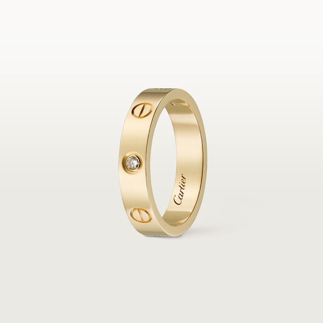 Gold ring with a diamond on a light gray background