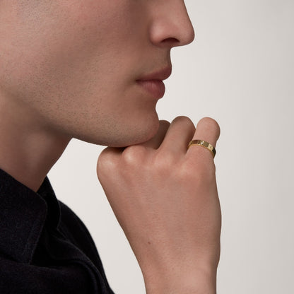 Close-up of a person wearing a gold ring on a neutral background