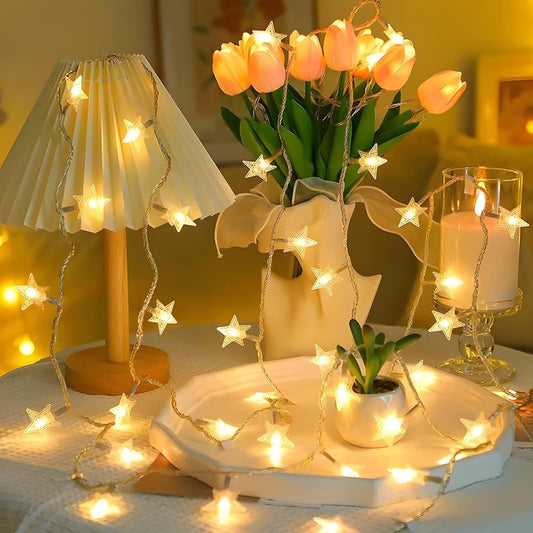 Decorative setup with string lights, flowers, and candles on a table.