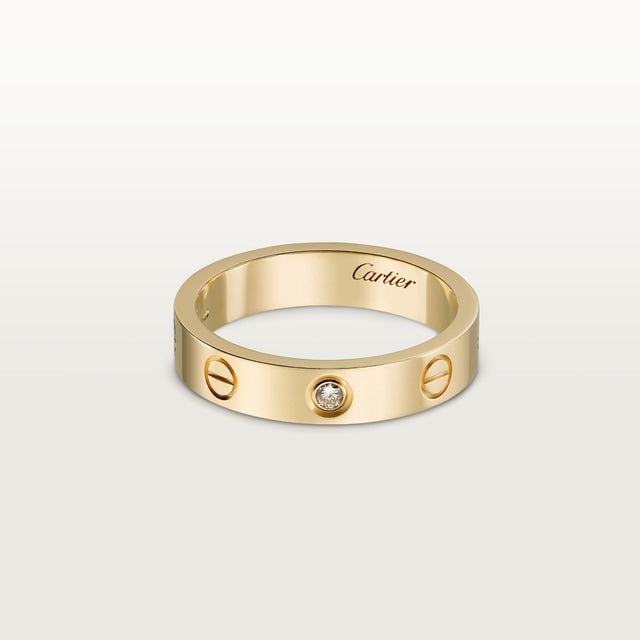 Gold Cartier ring with a diamond on a light gray background