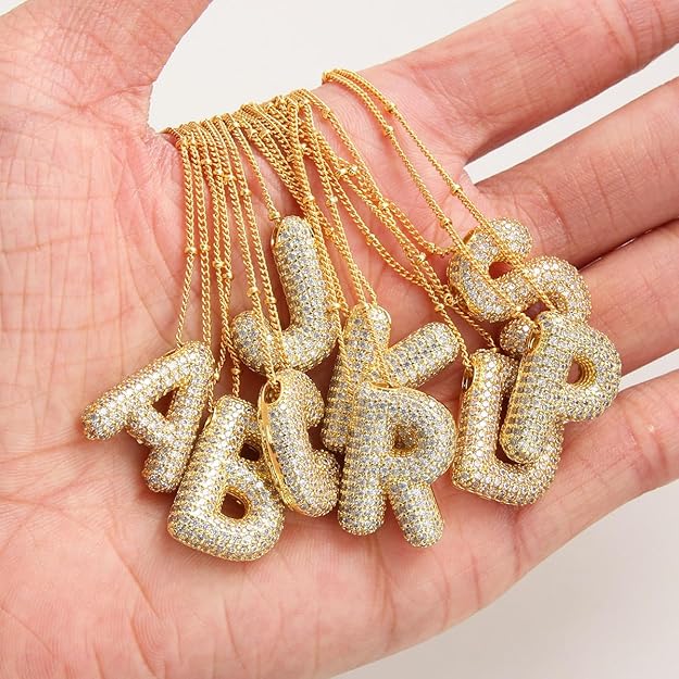 Gold letter pendants on chains held in a hand