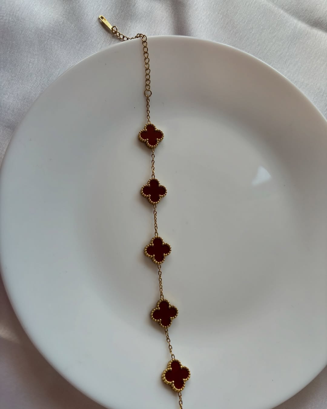 Bracelet with red floral charms on a white plate