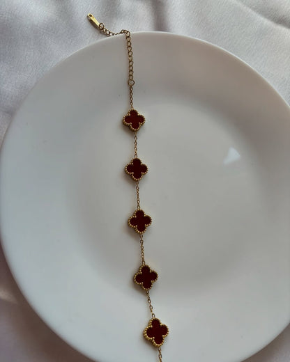 Bracelet with red floral charms on a white plate
