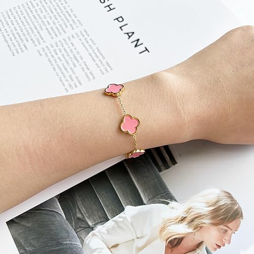Bracelet with pink flower-shaped charms on a wrist, with a magazine in the background.