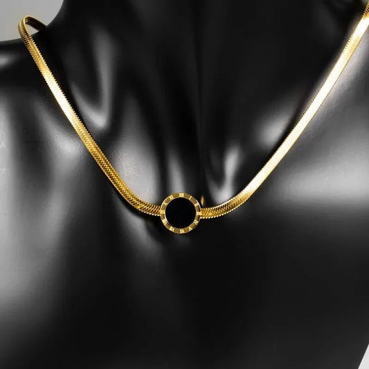 Gold necklace with a black circular pendant on a black mannequin.