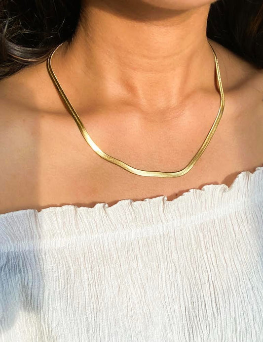Gold necklace worn by a person with a white garment