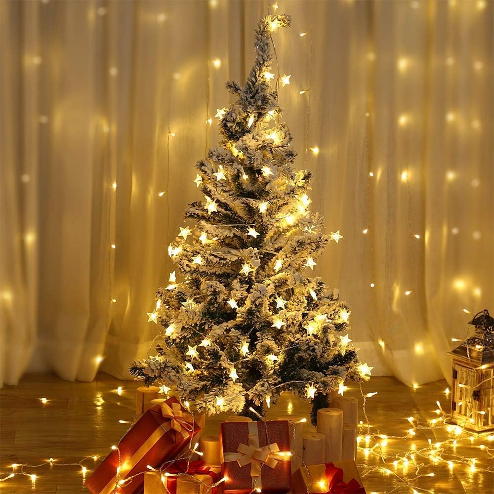 Decorated Christmas tree with lights and presents against a curtain backdrop
