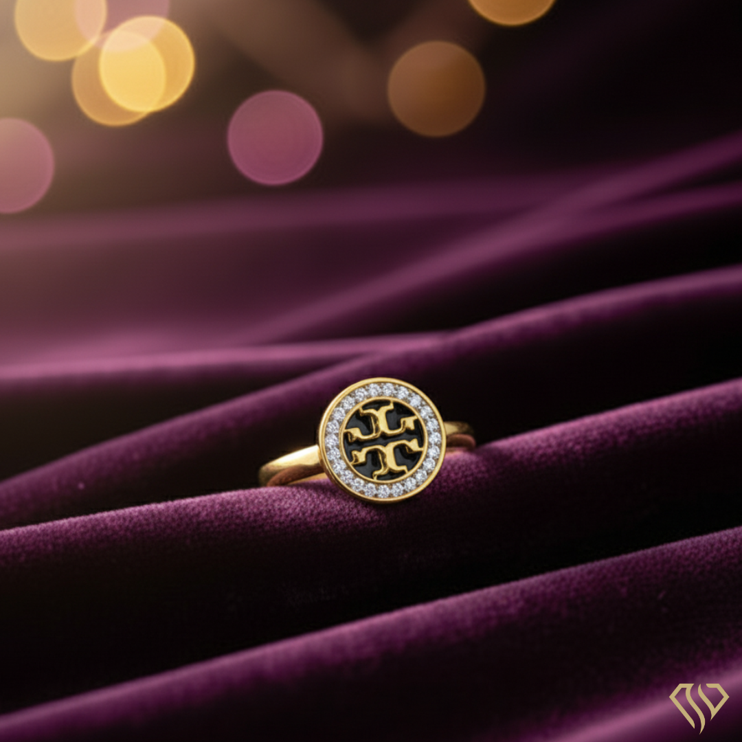 Gold ring with a circular design on a purple fabric background